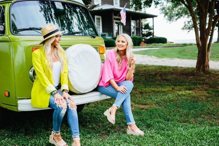 Women wearing colorful clothing sitting on a bumper of a VW van