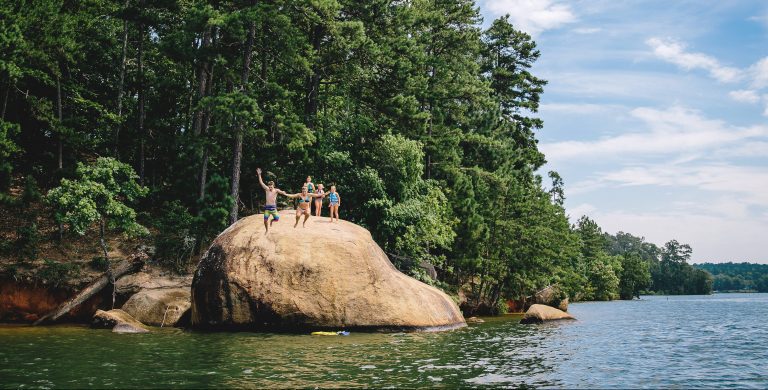 Couple jumping off of a rock into Lake Oconee