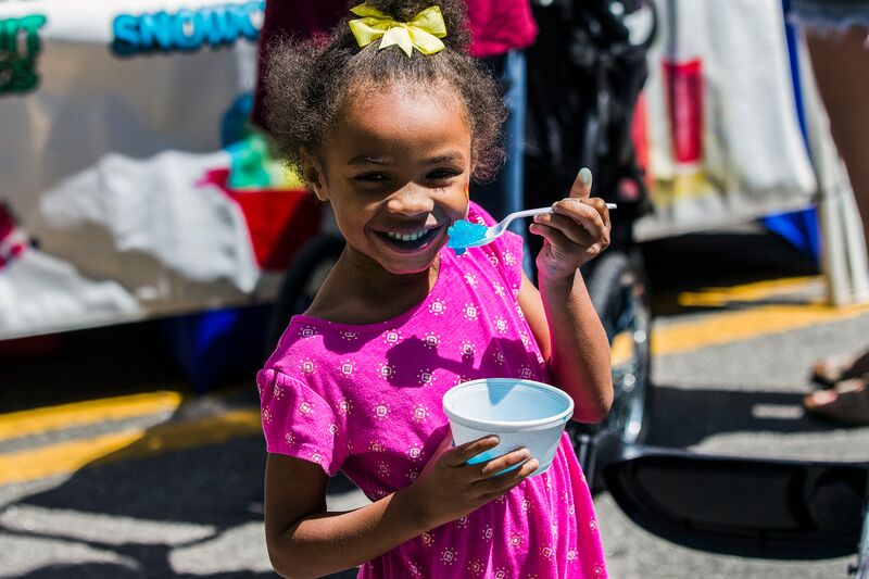 a young girl eating a blue snow cone